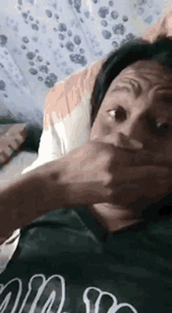 a woman is covering her mouth with her hand and making a funny face .