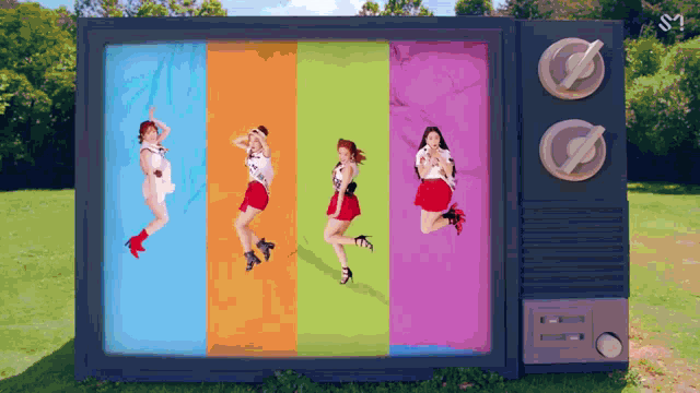 a group of girls are dancing in front of a colorful television