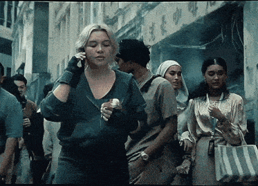 a woman talking on a cell phone while walking down a crowded street
