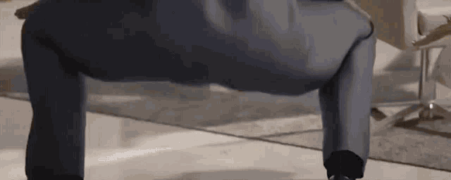 a man in a suit is doing push ups in a room .