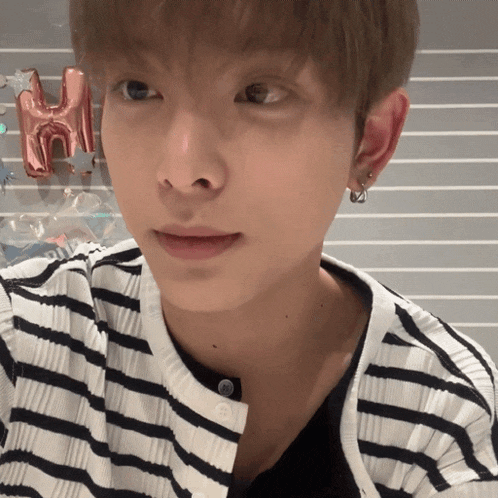 a close up of a person 's face with a striped shirt and earrings