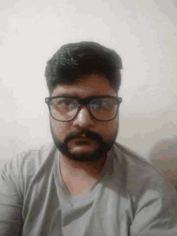 a man with a beard and glasses is taking a selfie .
