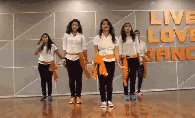 a group of women are dancing in front of a wall that says live love nancy