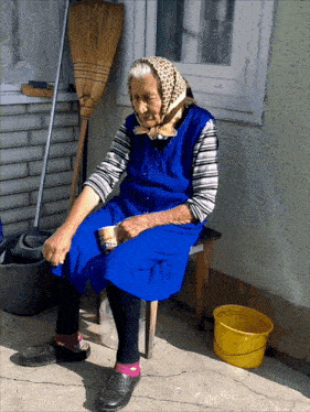 a woman in a blue dress sits on a bench with a yellow bucket in front of her