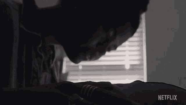 a man is laying on a bed with a ring on his finger and a netflix logo in the corner .