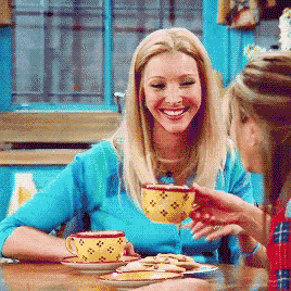 two women are sitting at a table drinking coffee