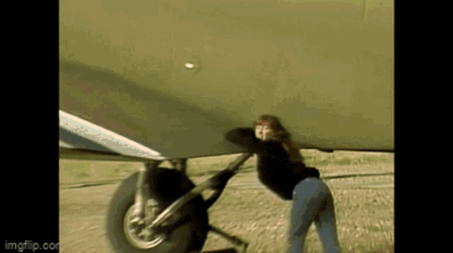 a woman is pushing a plane with the url imgflip.com in the lower right corner