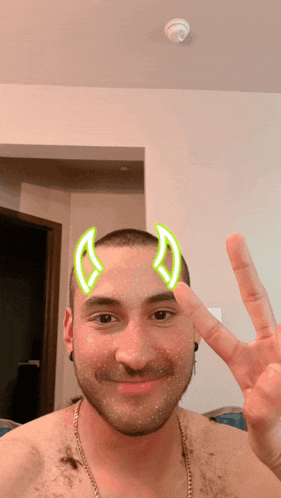a man without a shirt is making a peace sign with his hand