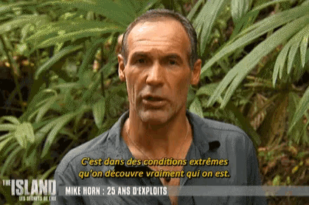 a man from the island is talking in front of some plants