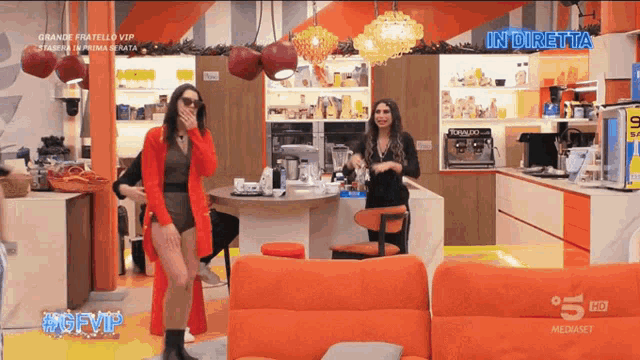 a woman in a red sweater is dancing in a living room with the words in diretta on the bottom