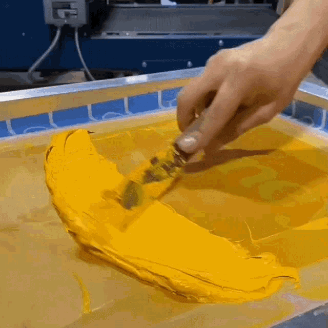 a person spreading yellow paint on a screen