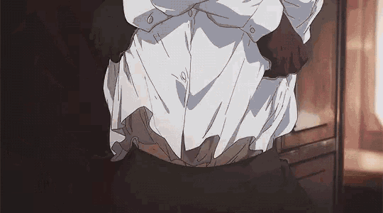 a man in a white shirt is standing in a dark room with his pants down