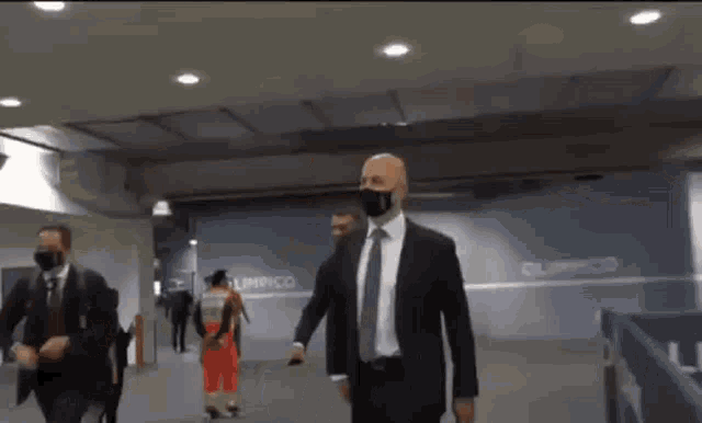 a man in a suit and tie is wearing a mask and walking through a tunnel .