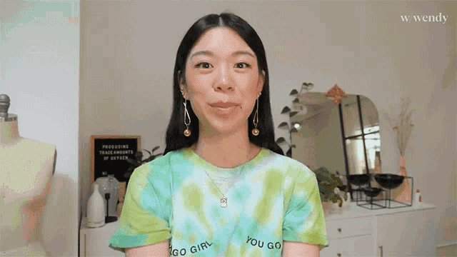 a woman wearing a tie dye shirt that says " go girl "