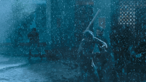 a man is running in the rain while another man stands in the background