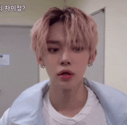 a close up of a young man with pink hair wearing a white shirt and a blue jacket .