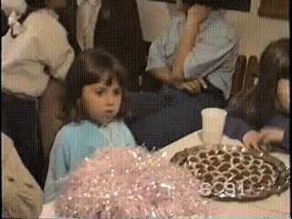a little girl is sitting at a table with a tray of food .