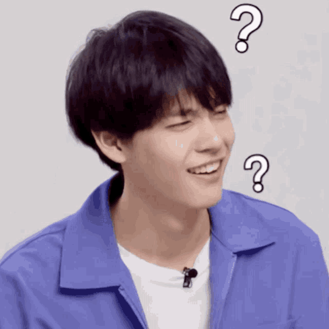a young man wearing a blue jacket and a white shirt is smiling with question marks above his head