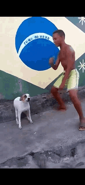 a man is dancing with a dog in front of a flag that says rumo ao hexa