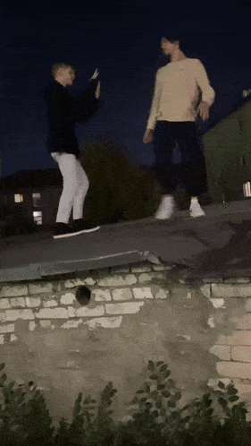 two young men standing on a roof with one wearing a sweatshirt that says ' abercrombie & fitch ' on it