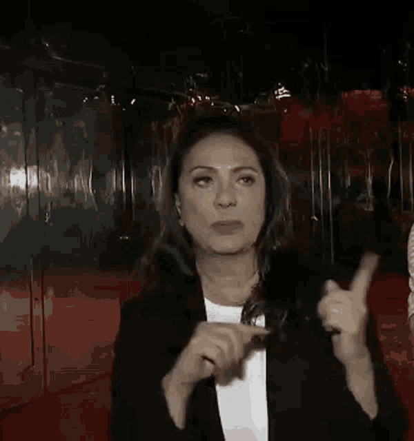 a woman in a black jacket is standing in front of a mirrored wall .