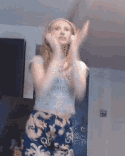 a woman wearing headphones is clapping her hands in a kitchen
