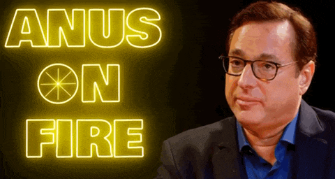 a man wearing glasses is sitting in front of a sign that says anus on fire