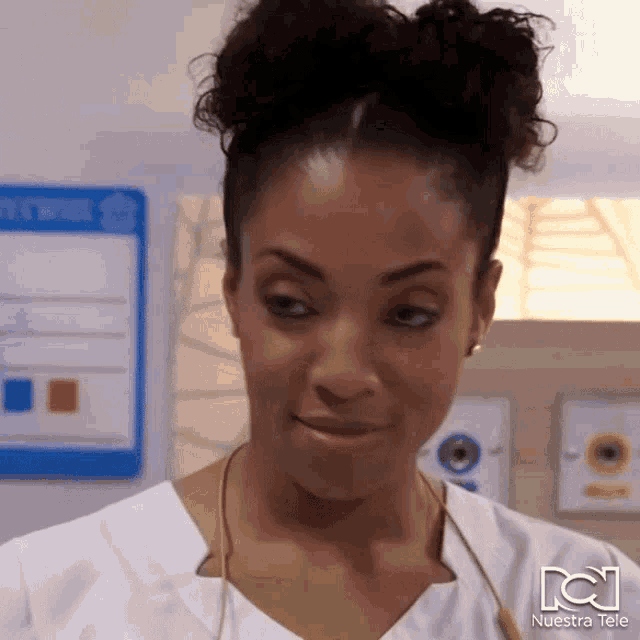 a woman wearing a white scrub top with a stethoscope around her neck has nuestra tele written on the bottom right