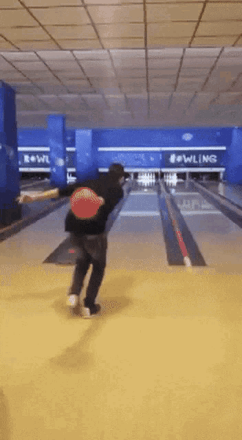 a person is throwing a bowling ball in a bowling alley with the word bowling on the wall