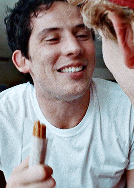 a man in a white shirt is smiling while holding a piece of food in his hand