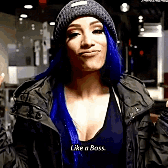 a woman with blue hair is wearing a beanie and a jacket and says like a boss
