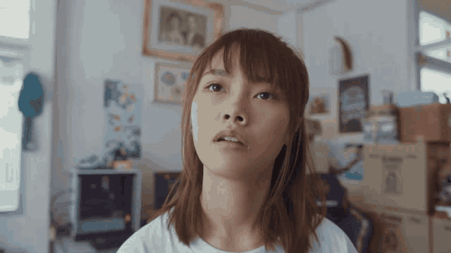 a woman in a white shirt is looking up at the camera