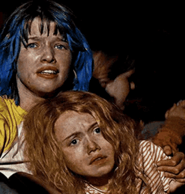 a woman with blue hair sits next to another woman with red hair