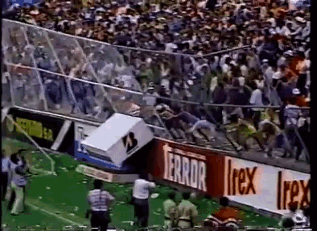 a crowd of people are gathered in a stadium with a sign that says terror .