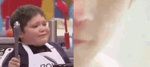 a young boy is crying while holding a fork and spoon in his hands .