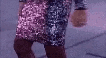 a woman in a pink and silver sequined dress is walking down a street .