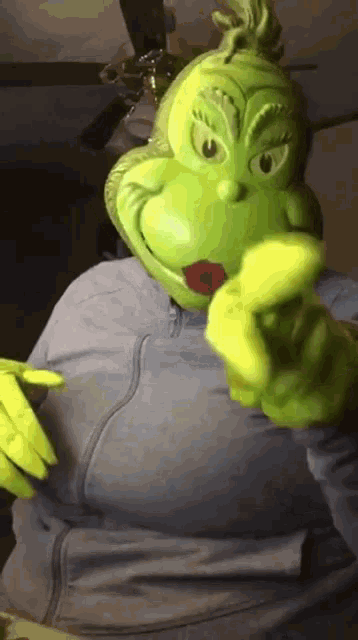 a woman is wearing a grinch mask and pointing