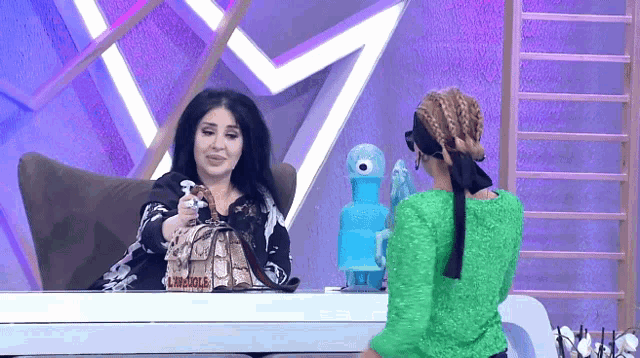 a woman in a green sweater is talking to another woman in a black shirt