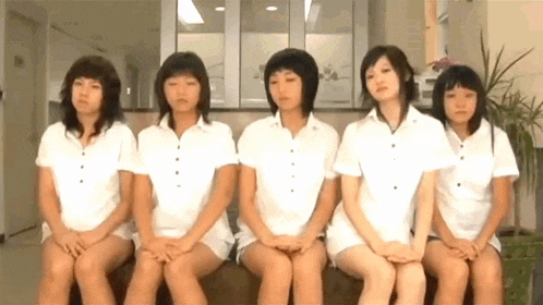 a group of young women are sitting next to each other on a couch .