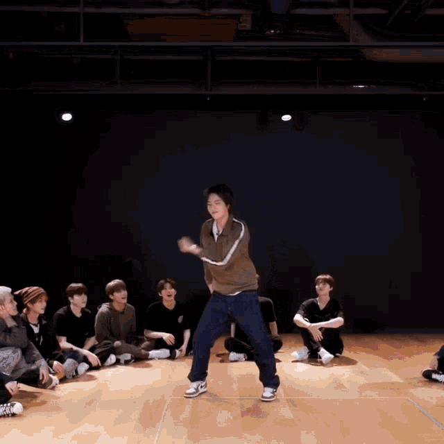 a man in a brown shirt and blue jeans is dancing on a dance floor .