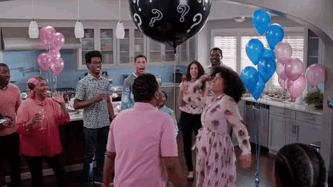a group of people are standing around a balloon with a question mark on it .