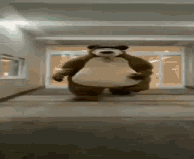 a teddy bear is standing in a hallway with a large belly .