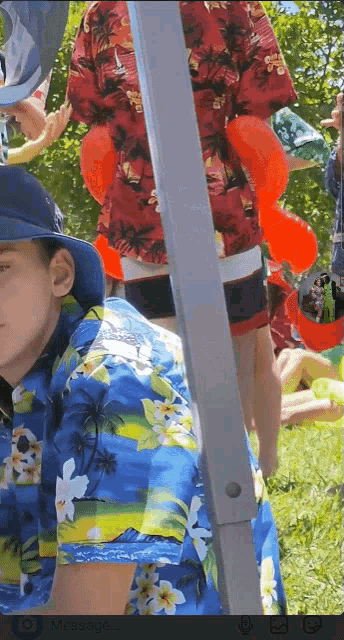 a boy wearing a blue hawaiian shirt is standing in a field