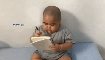 a baby is sitting on a bed holding a pen and a notebook .