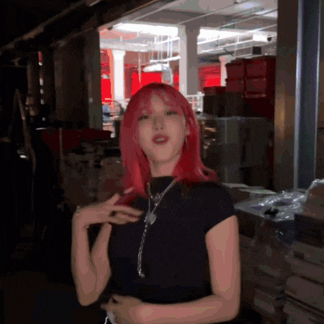 a woman with red hair and a black shirt is standing in a dark room