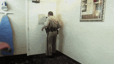 a police officer opens a door in a room with a blue ironing board
