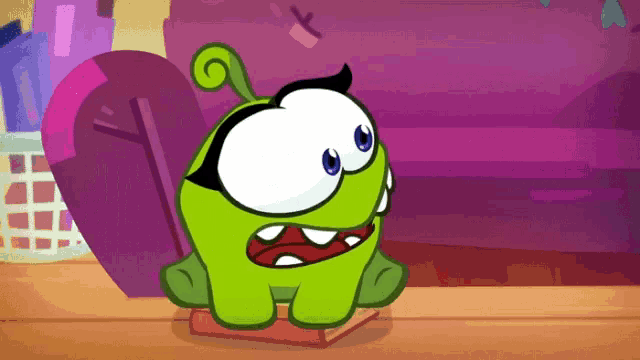 a green cartoon character is sitting on a wooden table with a purple background