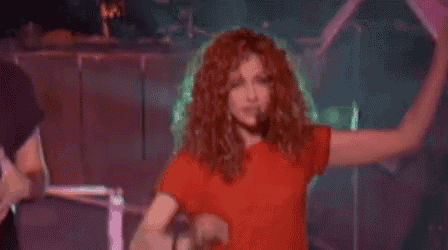 a woman is dancing on a stage with her arms in the air .