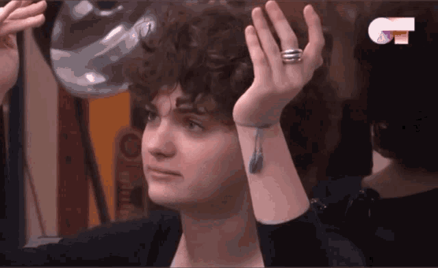 a woman with curly hair has a ring on her wrist