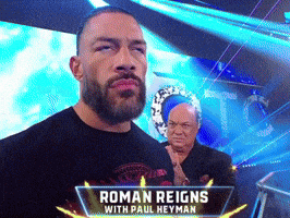 a man in a black shirt with roman reigns with paul heyman written on it